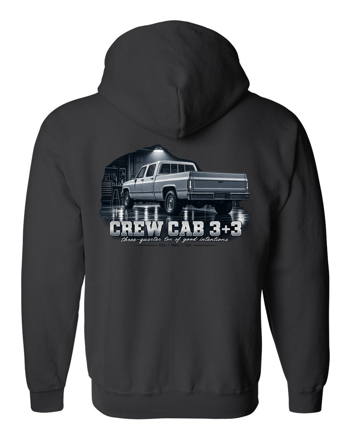 1985 C20 Squarebody crew cab in a garage night scene, print black zip hoodie back view with the design