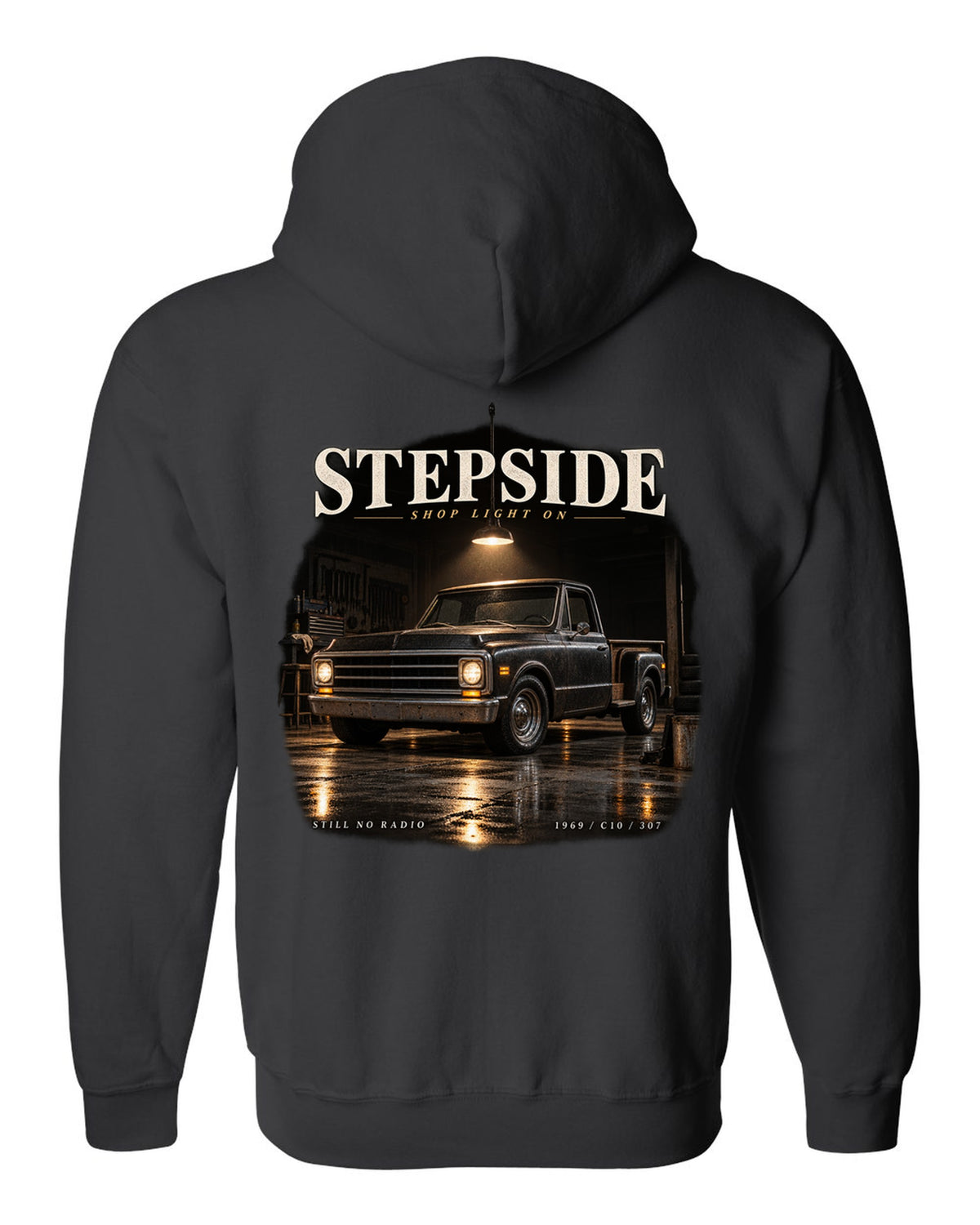 Chevy C10 Stepside under a shop light, garage night print black zip hoodie back view with the design