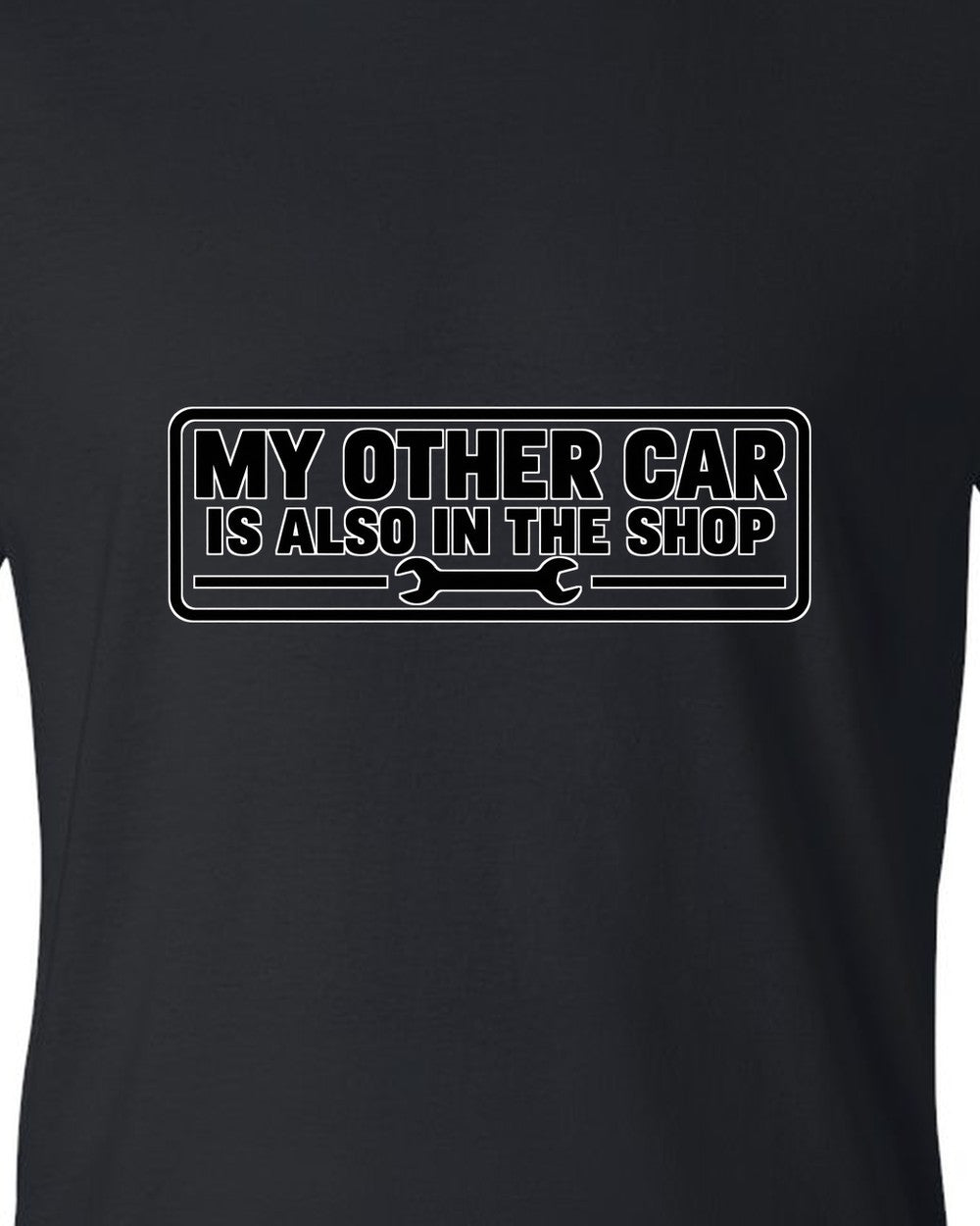 Bumper sticker rectangle with a small wrench icon black t-shirt close-up